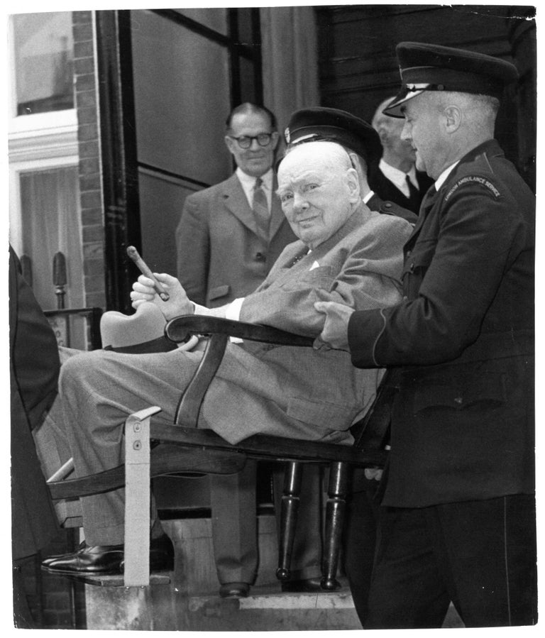 Item #005366 An original press photo of Sir Winston S. Churchill being carried out of Middlesex Hospital on 21 August, 1962, cigar in hand