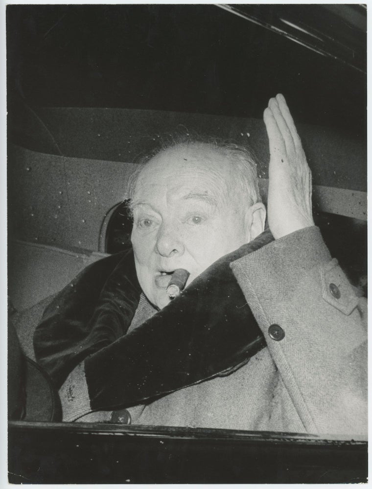 Item #005407 An original press photograph of Sir Winston S Churchill taken on 11 April 1963 capturing him waving while smoking a cigar as he leaves his Hyde Park Gate home for a holiday in Monte Carlo