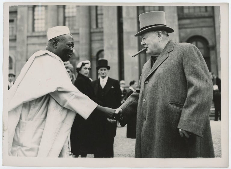Item #005572 An original press photograph of Prime Minister Winston S. Churchill shaking hands with the Ooni of Ife on 8 June 1953 on the grounds of Blenheim Palace during the Commonwealth Prime Ministers Conference